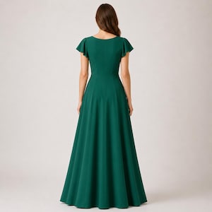 May include: A long, emerald green dress with short, flutter sleeves. The dress has a fitted bodice and a flowing, floor-length skirt. The back of the dress is visible, showing a simple, elegant design. The dress is made of a smooth, solid fabric.