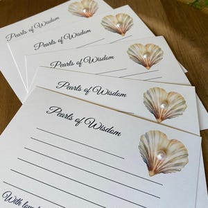May include: A stack of white stationery cards with the words "Pearls of Wisdom" in elegant script. Each card features a seashell illustration with a pearl. The cards have lined spaces for writing.