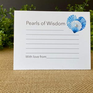 May include: A white card with the text "Pearls of Wisdom" and lines for writing. A blue and white seashell design with a pearl is in the upper right corner. The text "With love from" is at the bottom.