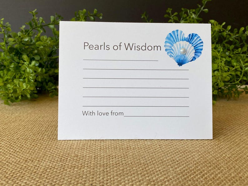 May include: A white card with the text "Pearls of Wisdom" and lines for writing. A blue and white seashell design with a pearl is in the upper right corner. The text "With love from" is at the bottom.