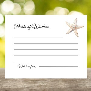 May include: A white card with the text "Pearls of Wisdom" and "With love from," printed in elegant script. A starfish with a pearl in the center is in the upper right corner. The card has lines for writing and is set against a blurred green background.