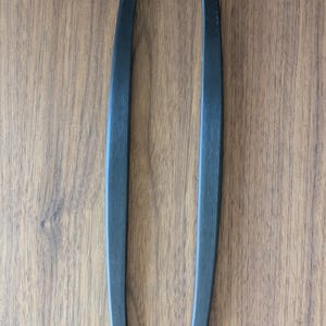 May include: Two black, rectangular cabinet pulls with a matte finish. The pulls are positioned vertically against a wood grain background. Each pull is approximately 6 inches in length.