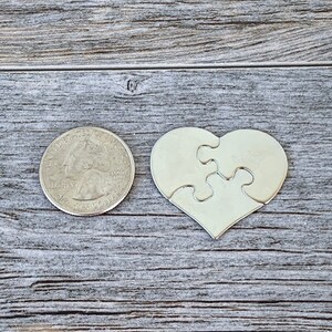 May include: A silver metal heart-shaped puzzle piece with four interlocking pieces. The puzzle piece is about the size of a US quarter.