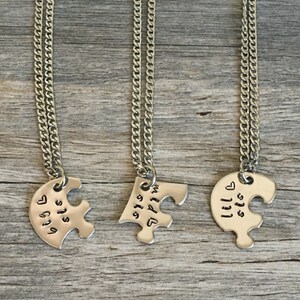 May include: Three silver necklaces with puzzle piece pendants. Each pendant has the words "Big Sis", "Little Sis", and "Big Sis" engraved on them.