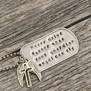 May include: Silver necklace with a dog tag pendant that reads "Never drive faster than your guardian angel can fly" and a silver charm with a cross and wings.