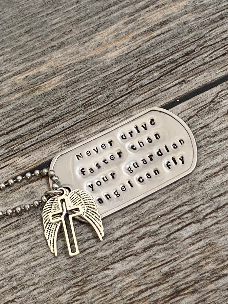 May include: Silver necklace with a dog tag pendant that reads "Never drive faster than your guardian angel can fly" and a silver charm with a cross and wings.