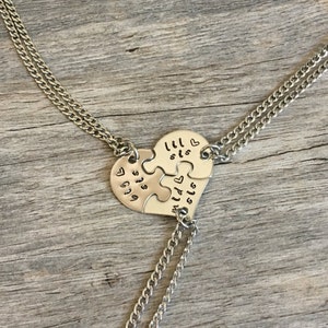 May include: Three silver necklaces with heart-shaped puzzle pieces that say "lil sis" and "big sis".