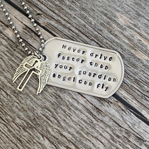 May include: Silver necklace with a dog tag pendant that reads "Never drive faster than your guardian angel can fly". The dog tag is attached to a silver chain with a small angel wing charm.