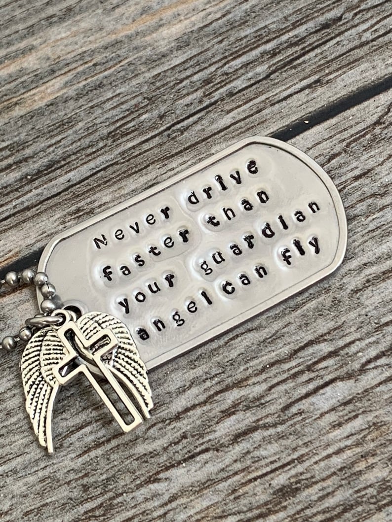 May include: Silver charm necklace with a silver angel wing and cross charm. The tag reads "Never drive faster than your guardian angel can fly."