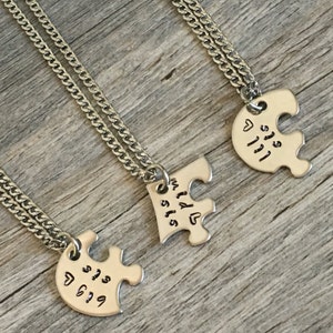 May include: Three silver necklaces with puzzle piece pendants. The pendants say "Big Sis", "Lil Sis", and "My Lil Sis".
