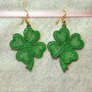 May include: A pair of green shamrock earrings with gold hooks. The shamrocks are made of delicate lace.