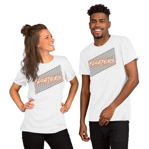 May include: White t-shirts with the word "FLOATERS" in orange and gray, with a decorative pattern. The shirts are short-sleeved and worn by two people, a man and a woman.