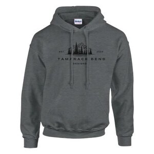 Puede incluir: Una sudadera con capucha gris oscuro con un gr&aacute;fico negro de monta&ntilde;a y &aacute;rboles y el texto "Tamarack Bend Designs" impreso en la parte delantera.