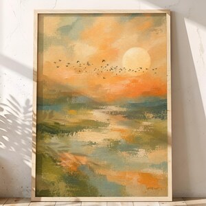 May include: A rectangular framed wall art print featuring an impressionistic landscape painting with a vibrant orange sunset, a pale yellow sun, and a flock of birds in flight over a green and blue marshland with reflective water surfaces.