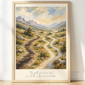 May include: A framed wall art print featuring a landscape painting of a mountain valley with two diverging dirt paths. The sky is filled with soft clouds. At the bottom, the text reads: The path you know best is not the only one available.