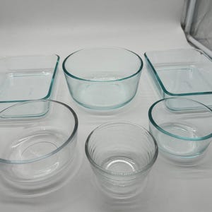 May include: A set of three ceramic nesting bowls in graduating sizes. The bowls are white with a speckled, textured finish and feature a slightly flared rim. The largest bowl measures approximately 8 inches in diameter.