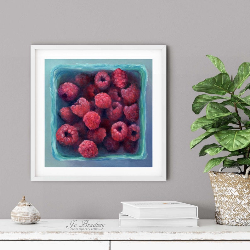 A bright turquoise blue and pink raspberry oil painting art print in a simple elegant picture frame on a dining room or living room wall. Square art print on archival fine art paper of summer fruit still life 4x4 5x5 6x6 8x8 10x10 12x12 inch