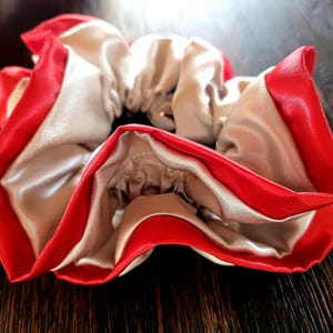 Könnte beinhalten: Ein rotes und weißes Satin-Haargummi mit gerafftem Design.