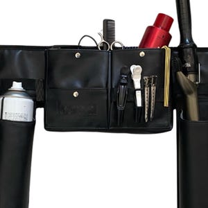 May include: Black leather stylist belt with multiple pockets and holders for tools, including a round brush, hairspray, shears, and a curling iron.
