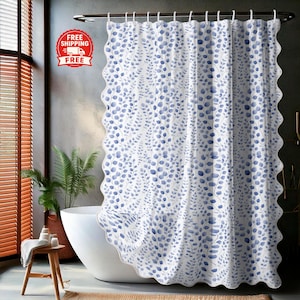 Könnte beinhalten: Weißer Duschvorhang mit blauem Blättermuster. Der Vorhang hat einen gewellten Rand und hängt an einer Metallstange. Das Badezimmer umfasst eine weiße Badewanne, einen Holzschemel und eine Topfpflanze.