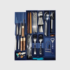 Op de afbeelding: Een marineblauwe bestekorganizer gevuld met diverse zilverwerk, waaronder messen, vorken, lepels, eetstokjes en serveerbenodigdheden. De organizer bevat ook een flesopener en een kurkentrekker. De gebruiksvoorwerpen zijn gemaakt van roestvrij staal en hout.