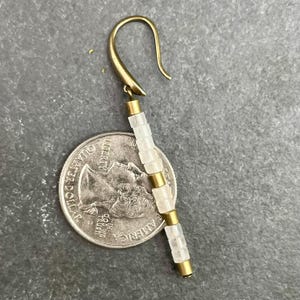 May include: A gold earring with a white stone dangle. The dangle is made of multiple square-shaped stones with gold spacers between each stone.