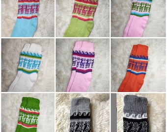 May include: A collection of colorful socks with llama patterns. The socks come in various colors, including blue, green, pink, white, and orange. Each sock features a patterned cuff with llama designs and geometric borders. The socks are displayed on a fluffy, white surface.