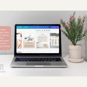 May include: A laptop computer displaying a digital design program with four open pages. The pages feature a variety of designs, including a floral pattern, a beach scene, and a text-based page. The laptop is on a white table with a potted plant with pink flowers.