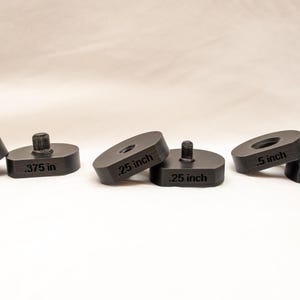 Könnte beinhalten: Fünf schwarze Kunststoffabstandshalter in verschiedenen Größen: 0,95 cm, 0,64 cm und 1,27 cm. Jeder Abstandshalter hat einen kleinen, erhöhten Mittelpfosten.