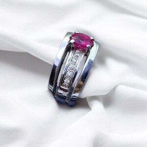 K&ouml;nnte beinhalten: Ein silberner Ring mit einem rosafarbenen ovalen Edelstein und einer Reihe kleiner, klarer Edelsteine.