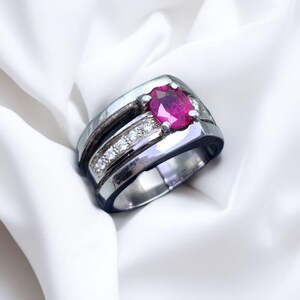 K&ouml;nnte beinhalten: Ein silberner Ring mit einem roten Edelstein und einer Reihe kleinerer wei&szlig;er Edelsteine.