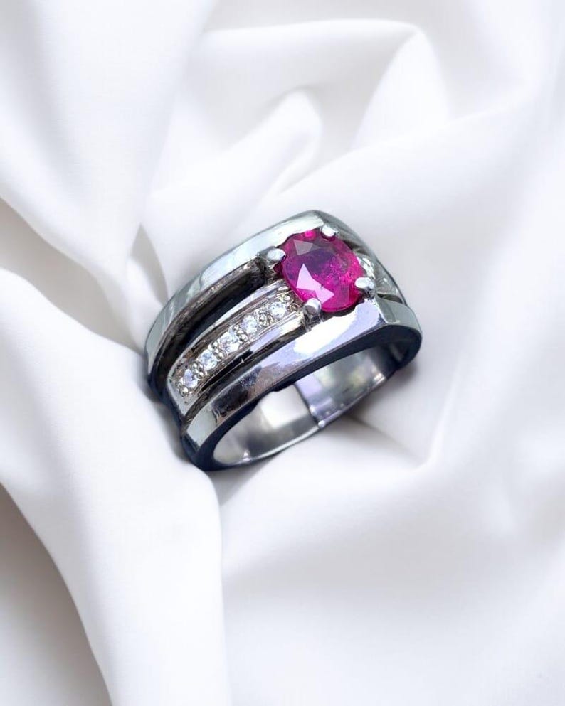 K&ouml;nnte beinhalten: Ein silberner Ring mit einem roten Edelstein und einer Reihe kleinerer wei&szlig;er Edelsteine.