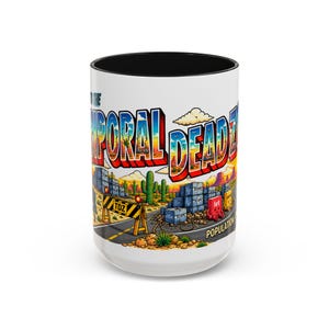 May include: A white ceramic mug with a black interior featuring a colourful graphic of a desert landscape. The text reads "WELCOME TO THE TEMPORAL DEAD ZONE" with "POPULATION:" visible at the bottom. The scene includes cacti, road barriers, and blocks.
