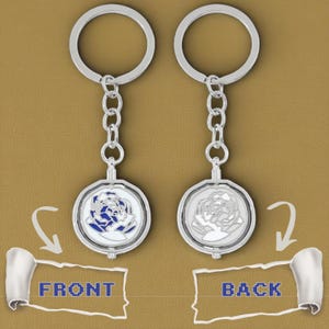 May include: Two silver keychains with circular rings and chain links. Each keychain features a round pendant with a rose design. One pendant has a blue rose, the other a silver rose. The word "FRONT" and "BACK" are indicated.