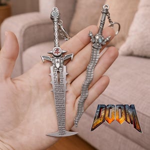 May include: Two silver-colored sword keychains with intricate designs. One has a straight blade with etched text, the other a curved blade. The DOOM logo is visible in the bottom right corner.
