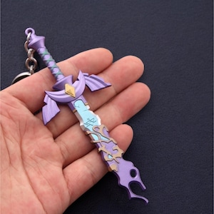 May include: A purple and blue sword keychain with gold accents. The sword features a crescent moon design and intricate details.