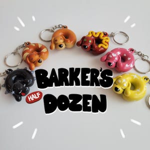 May include: Six colorful dog-shaped keychains, each with a different colored donut, are arranged in a circle on a white surface. The keychains are labeled "Barker's Half Dozen".