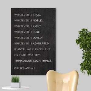 May include: A framed wall art print with the text "WHATEVER IS TRUE...PHILIPPIANS 4:8" in white on a dark background. The room features a yellow armchair, a small white side table, a potted plant, and a decorative tree.