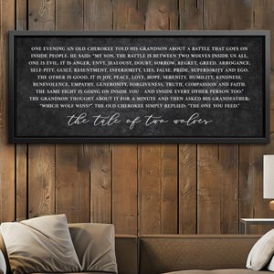 May include: A framed black and white wall art piece with the text "The Tale of Two Wolves". The text is a quote about the battle between good and evil within people. The artwork is displayed on a wooden wall.