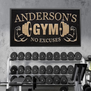 May include: A gym interior featuring a sign that reads "ANDERSON'S GYM" with a barbell and flexing arm graphic. Below the sign are rows of dumbbells, barbells, and weight benches. The sign is black with gold lettering.