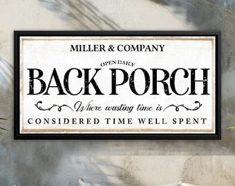 Pode incluir: Uma placa emoldurada com o texto "MILLER & COMPANY BACK PORCH" em letras pretas. A placa também inclui as frases "OPEN DAILY" e "Where wasting time is CONSIDERED TIME WELL SPENT."