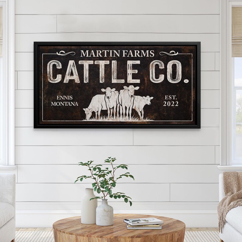 Może przedstawiać: Oprawiony znak z napisem "MARTIN FARMS CATTLE CO." w białych literach. Znak przedstawia ilustrację kilku kr&oacute;w oraz napis "ENNIS MONTANA EST. 2022" w kolorze białym. Znak ma ciemnobrązowe tło i czarną ramę.