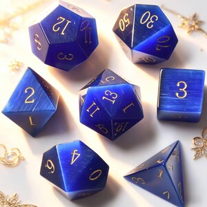 Puede incluir: Un conjunto de siete dados de piedras preciosas azules con números dorados. Los dados tienen varias formas, incluyendo un d4, d6, d8, d10, d12, d20 y un cubo. Los dados están colocados sobre una superficie blanca.