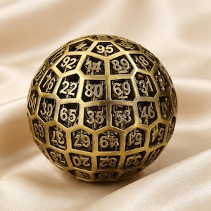 May include: A spherical object with a metallic gold finish featuring a hollow, grid-like structure. Each individual cell within the lattice contains a raised, embossed number, including visible digits such as 95, 92, 14, 89, 22, 80, 69, 31, 60, 39, 65, 35, 53, 46, 37, 67, 49, 51, 20, 82, and 33.