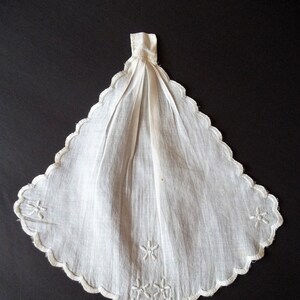 May include: White cotton handkerchief with scalloped edges and embroidered floral designs.
