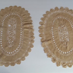 May include: Two oval crocheted doilies in a beige colour. The doilies have a delicate lace pattern and are perfect for adding a touch of elegance to any home.