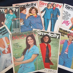May include: A collection of vintage Simplicity and McCall's fashion magazines. The covers feature models in 1970s clothing, including dresses, jumpsuits, and suits. The magazines have titles like "Simplicity fashion news" and "Carefree Patterns".