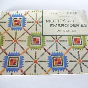 Puede incluir: Un libro de tapa blanda rectangular titulado D.M.C. Library Motifs for Embroideries 7th Series. La portada presenta un patrón geométrico repetitivo de cuadrados azules y verdes con centros naranjas conectados por líneas negras finas sobre un fondo beige.