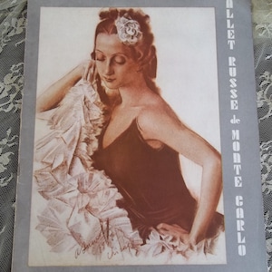 May include: A black and white illustration of a woman wearing a white flower in her hair and a black dress. The image is titled "Ballet Russe de Monte Carlo".