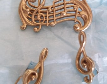 Conjunto de joyería musical de mediados de siglo con broche y pendientes de clave de sol vintage en tono dorado.